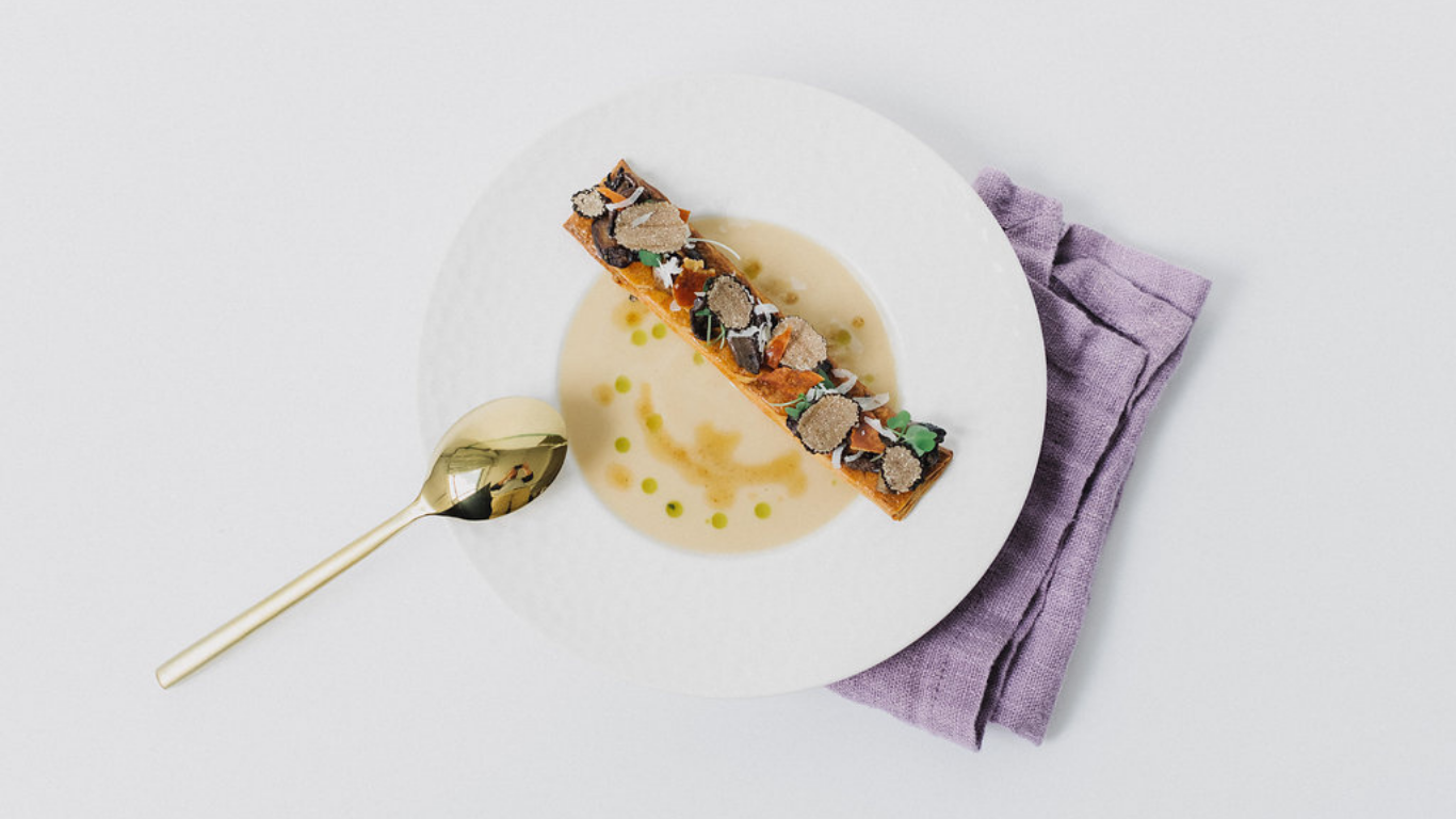 A server presenting a selection of vibrant hors d’oeuvres on a white tray, with elle cuisine napkins in hand.