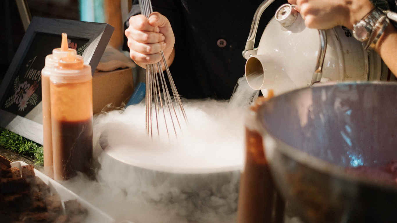 Chef creating a dramatic dessert presentation with liquid nitrogen and rich sauces at an elle cuisine event.
