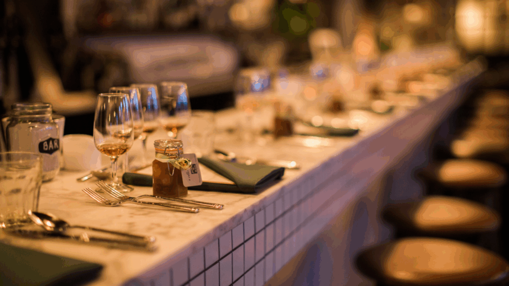 A beautifully set dining bar with glasses, flatware, and soft candlelight prepared for a holiday gathering.