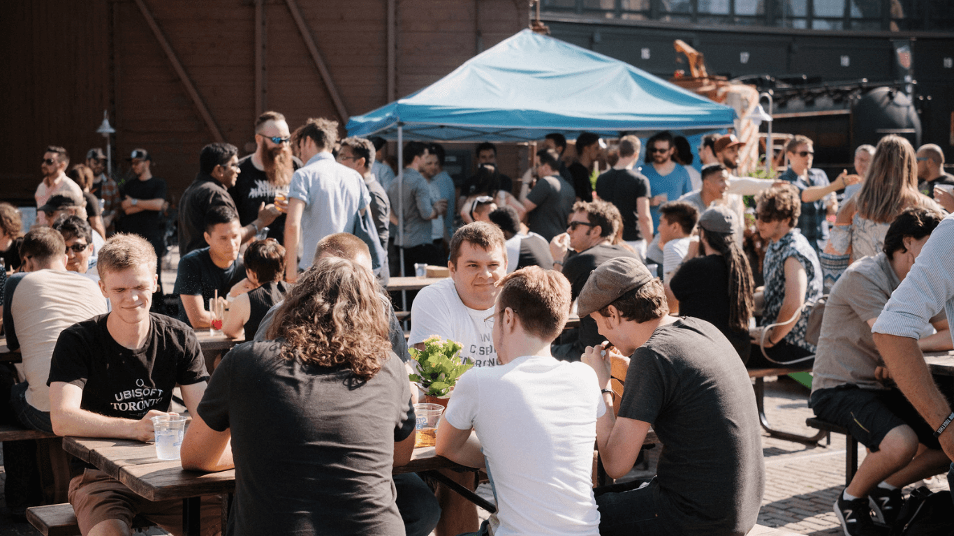 Attendees enjoying casual outdoor catering at long communal tables during a corporate gathering in Toronto.